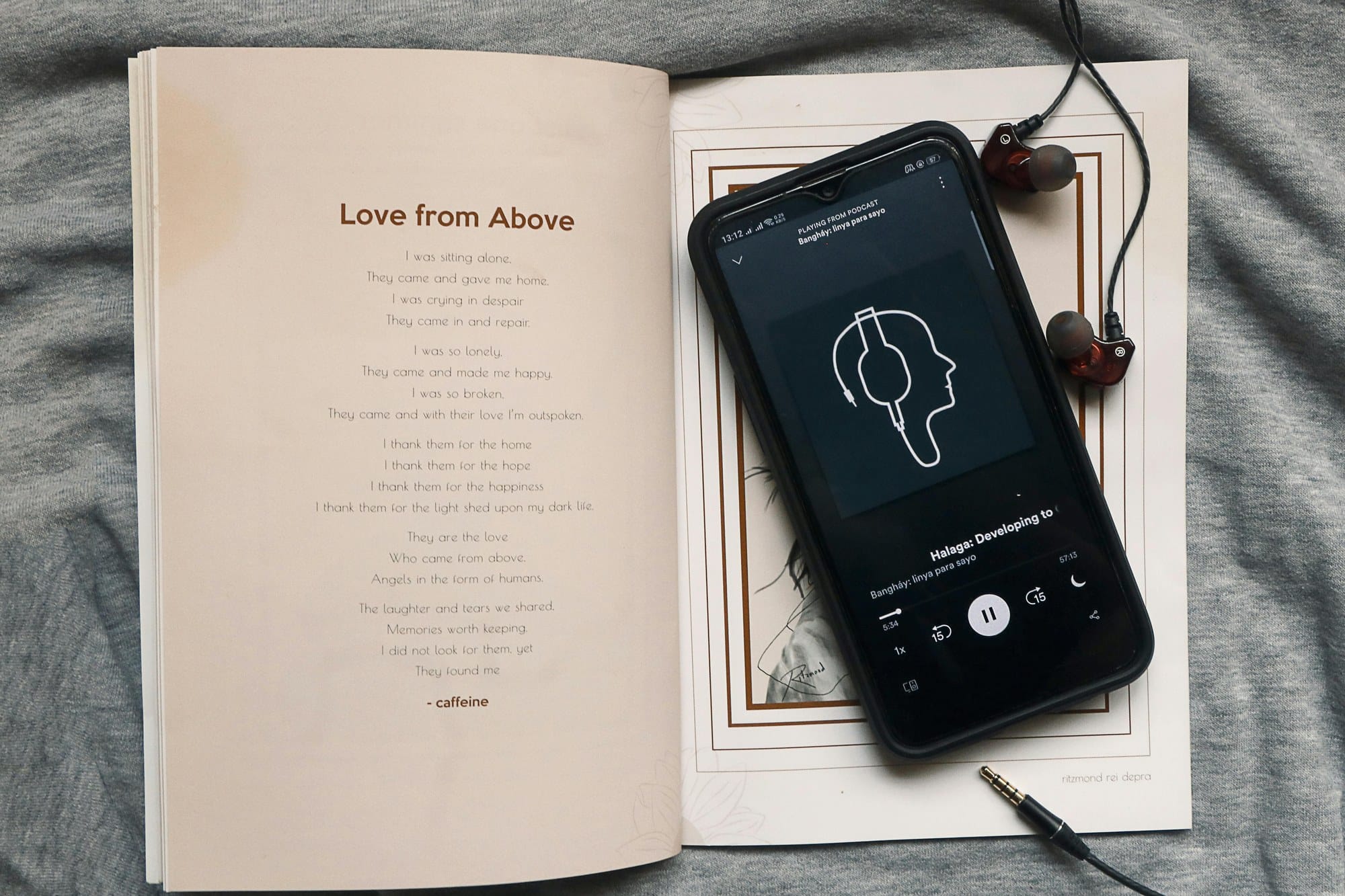 開いた本の上にスマートフォンとイヤホンが置かれている