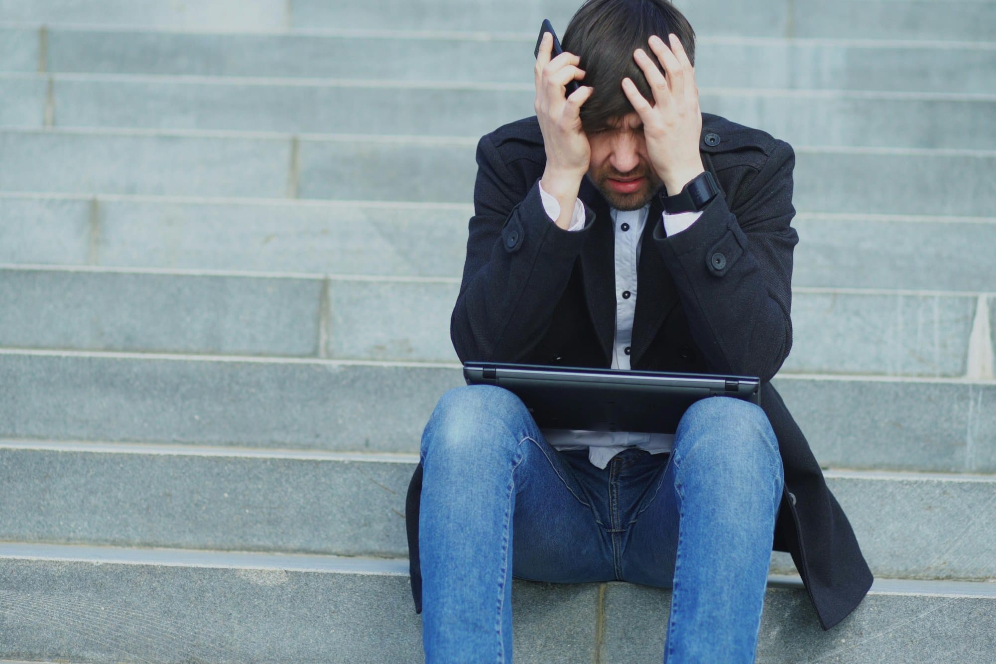 ノートパソコンの前で頭を抱える男性