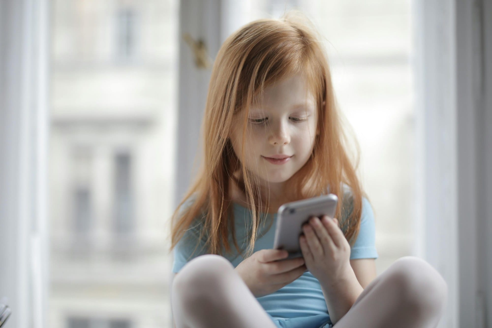 Child using an iPhone by the window